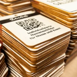 Mehrere gestapelte Holz-Namensschilder mit QR-Codes und individuellen Firmenlogos für Messe-Einsatz