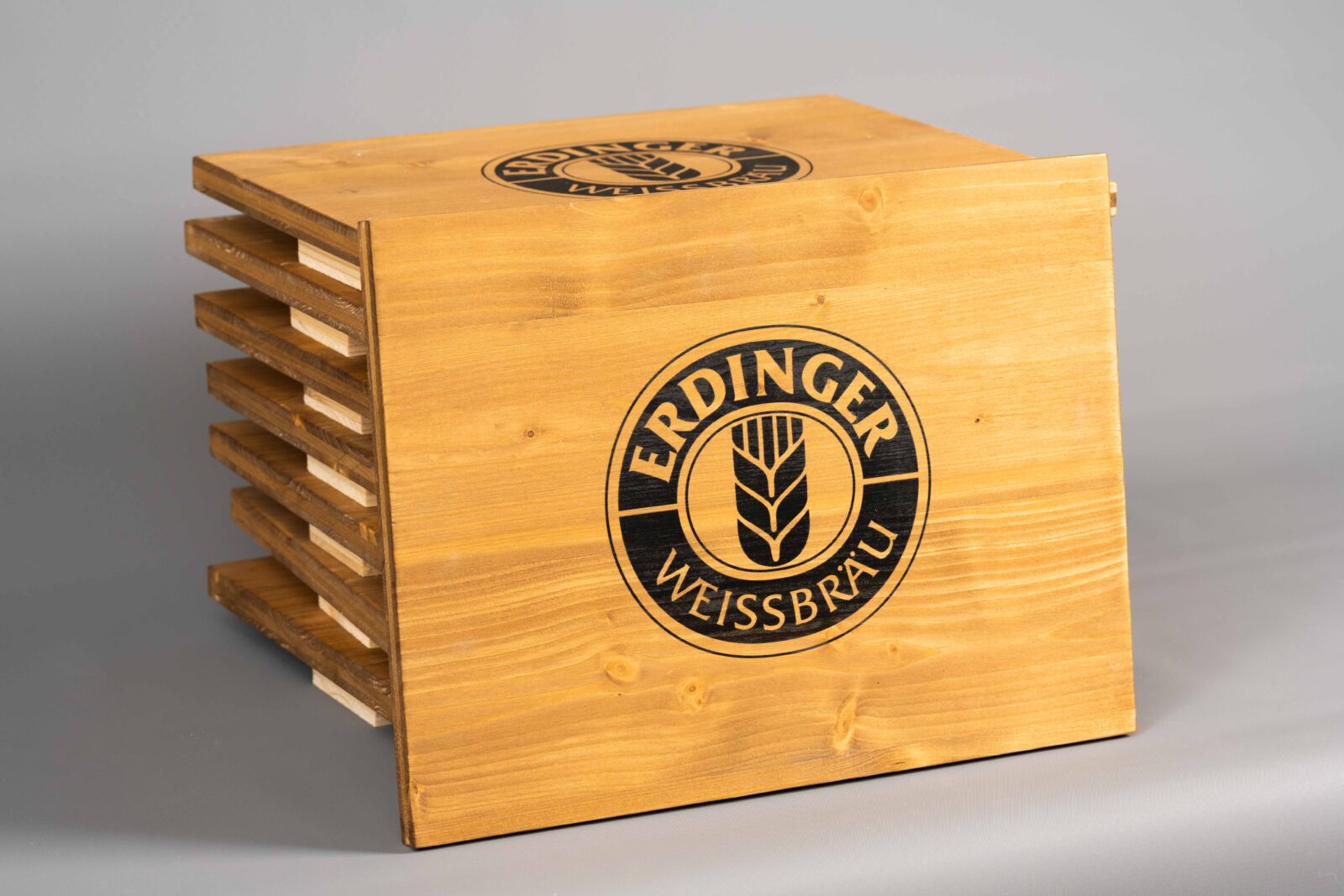 Sitzauflagen aus Holz für Bierkästen mit Brauerei-Logo zentriert bedruckt. Man sieht die schöne Maserung des Holzes.