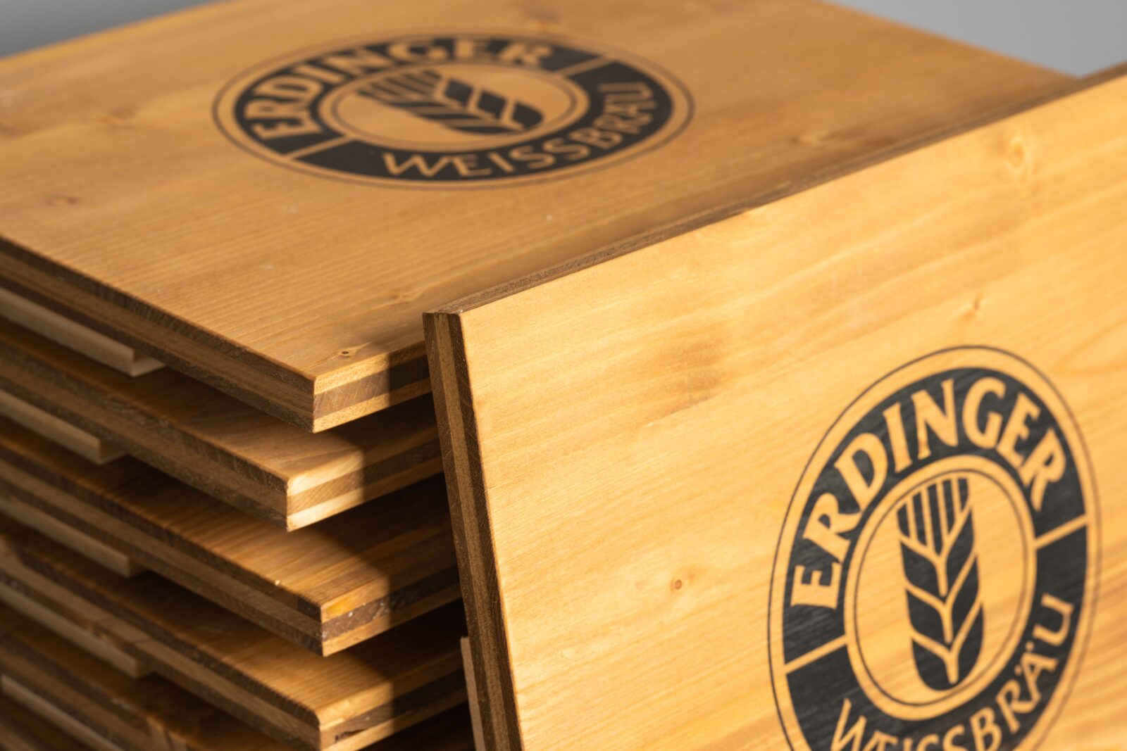 Bierkistenauflagen zum Sitzen mit Brauerei-Logo zentriert bedruckt. Man sieht die schöne Maserung des Holzes.