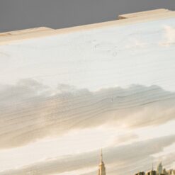 Fotodruck auf Holzlatten. Man sieht die separaten Latten von der Seite, sowie das Holz, was die Latten verbindet und von hinten oben rausschaut. Die schöne Maserung des Holzes gibt das Bild von dem Himmel über New York City einen schönen Charakter