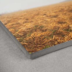 Die Ecke eines Fotos auf MDF gedruckt. Man sieht das schwarze MDF von der Seite und ein Lanfdschaftsfoto auf der glatten Oberfläche.