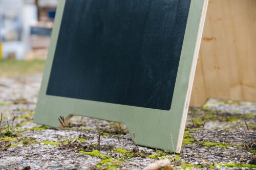 Holz-Kundenstopper mit bedruckter Fläche zum selbst beschreiben auf dem Gehweg vor einem Geschäft