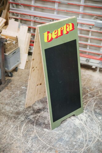 Holz-Kundenstopper mit einem großen, schwarzen, Rechteck bedruckt.