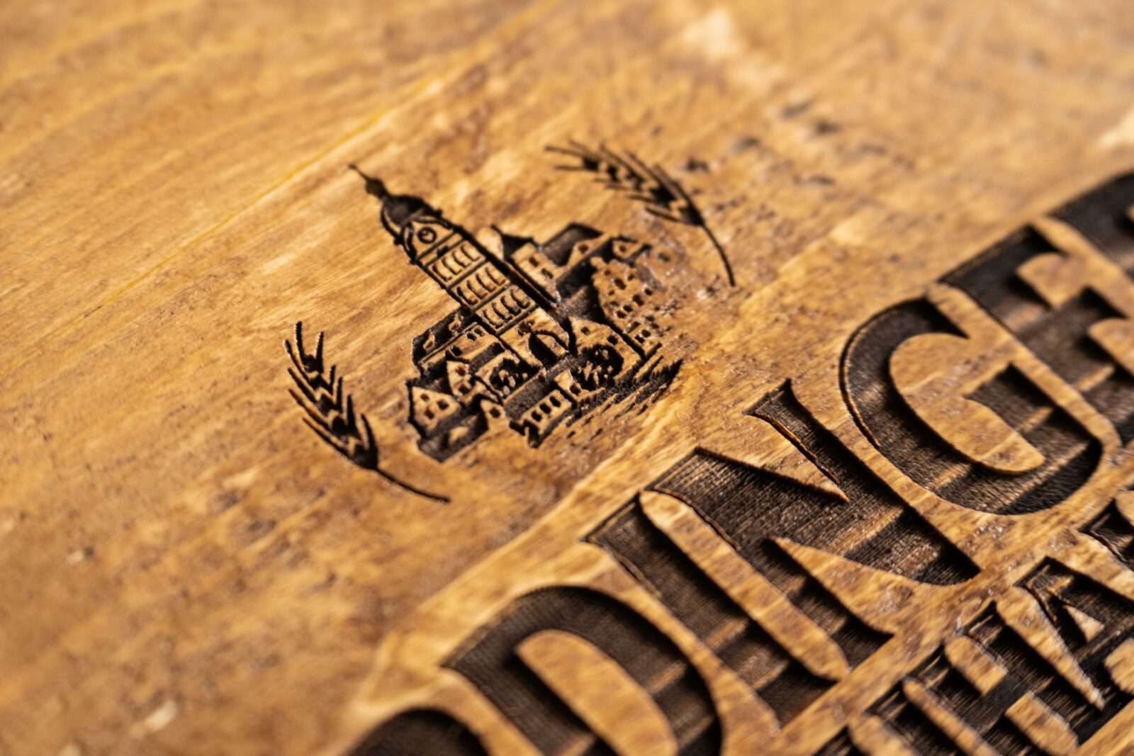 Detailreiche Lasergravur mit Logo und Schriftzug auf einer Bierkistenauflage aus Altholz.