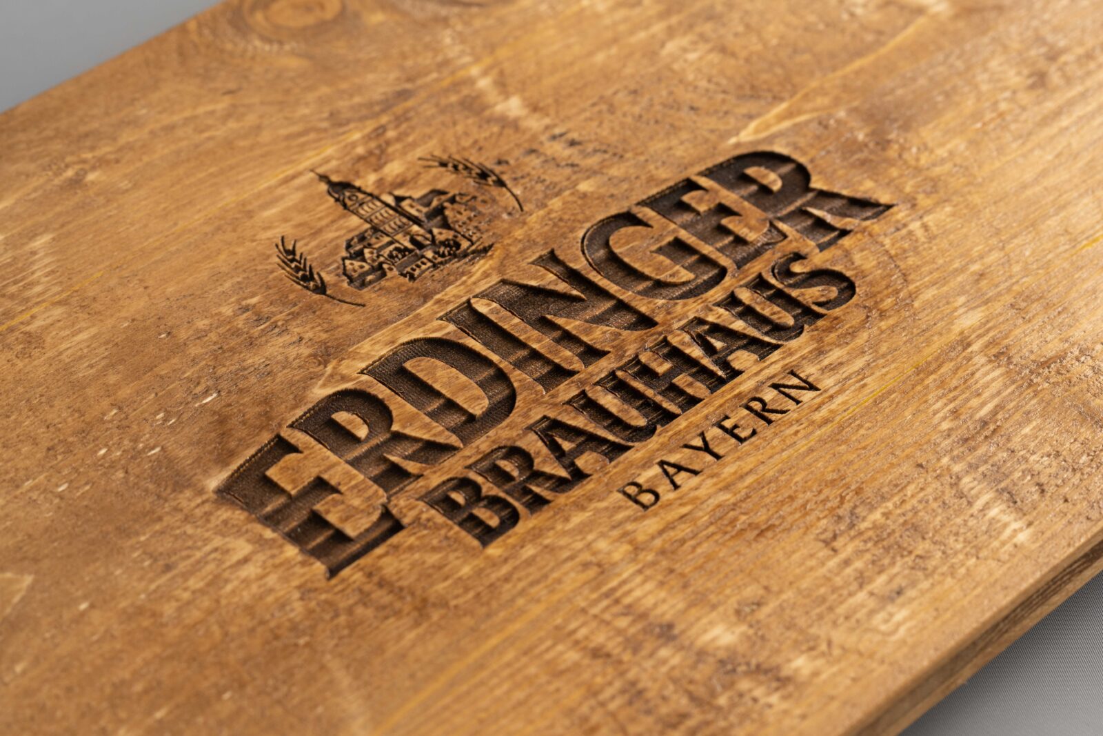 Breite Bierkistenauflage aus rauem Altholz mit warmer Beize und Lasergravur für zwei Getränkekisten.