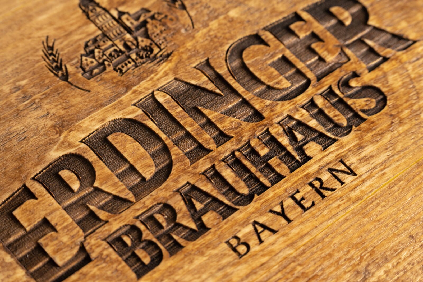 Lasergravur mit Logo und Schriftzug auf einer Bierkistenauflage aus Altholz.