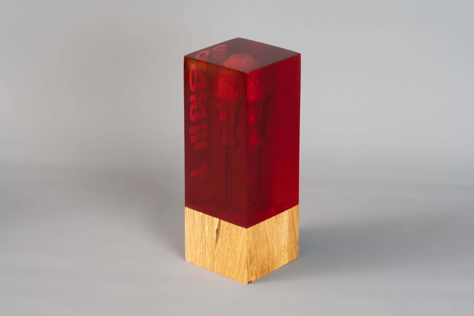 Ein Pokal von hinten. Man sieht in dem roten Kunstharz einen Schraubenzieher suspendiert.