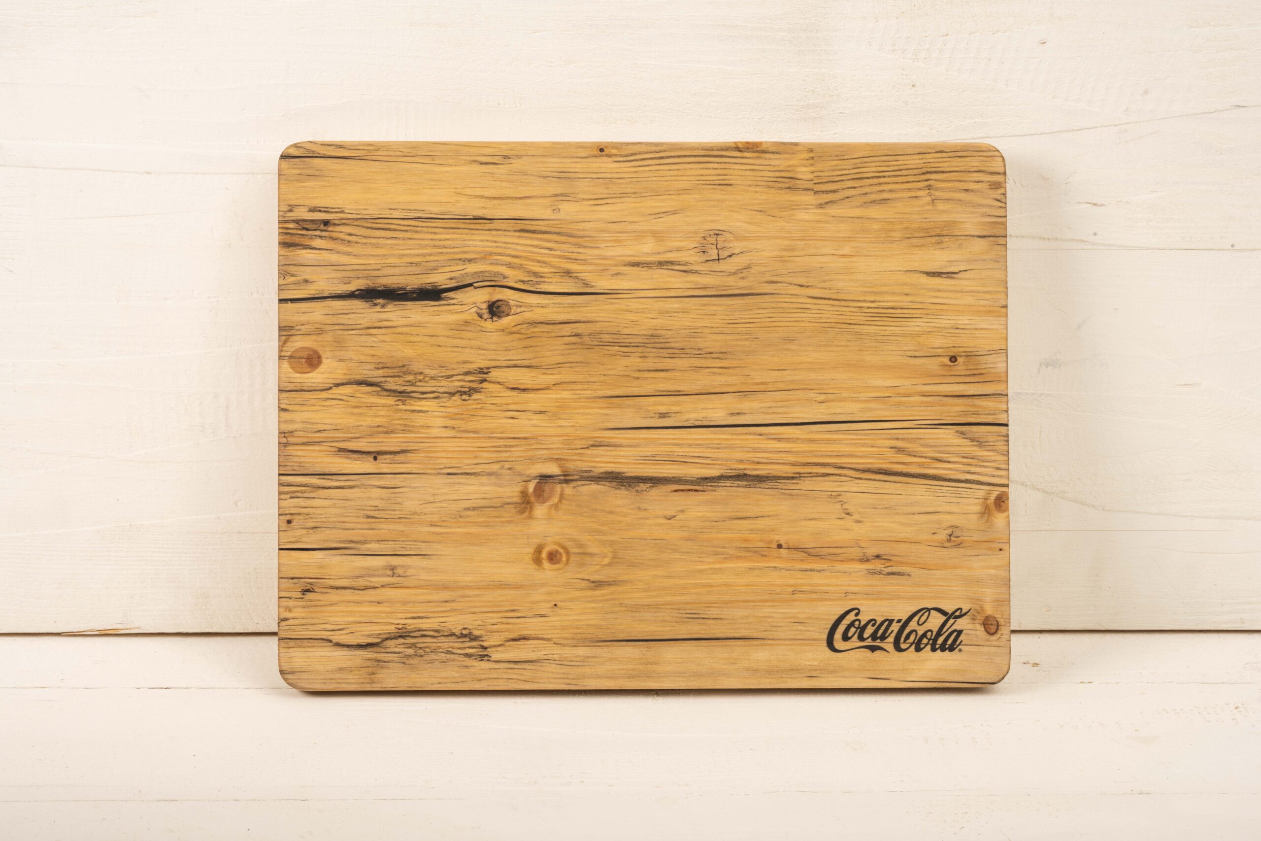 Kistenauflage aus Holz mit Coca-Cola Logo in der Ecke klein bedruckt.